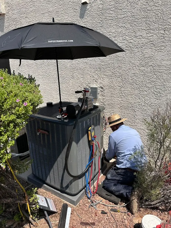 HVAC technician performing outdoor AC maintenance in Dracut