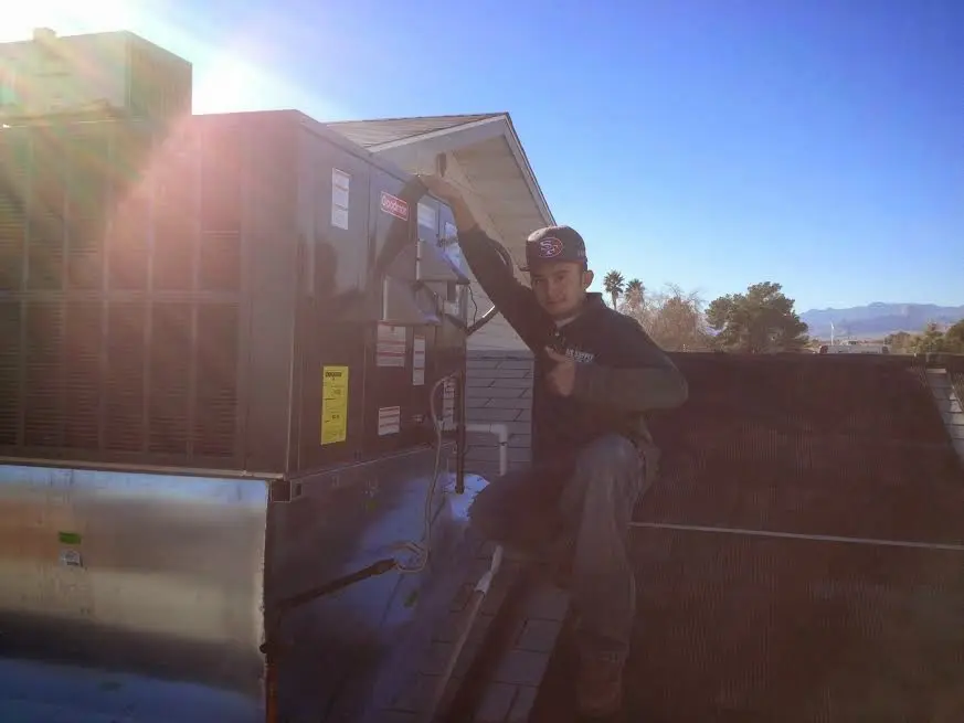 HVAC technician performing AC Tune-Up on a rooftop unit in Dracut